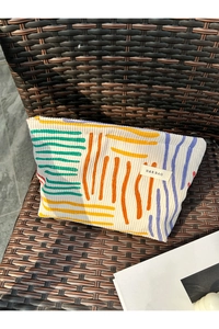 Detailed texture of a corduroy cosmetic bag with abstract art patterns on a woven chair