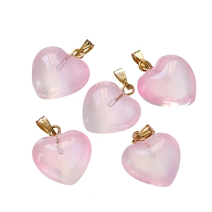 Macro shot of five translucent pink heart pendants with golden metal loops