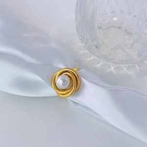 Elegant gold spiral pearl ring for women on white silk background with glass decor
