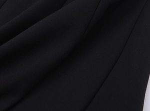 Close-up of the black dress fabric texture showing fine weave and high-quality drape