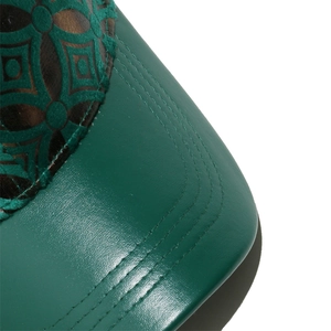 Close-up of green leather baseball cap with geometric stitching and textured fabric details