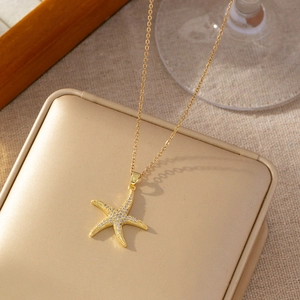 Close-up of golden starfish pendant necklace with pavé crystal inlay on jewelry box