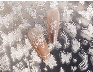 Vue macro d'autocollants 3D papillon pour ongles avec texture en relief et perles blanches
