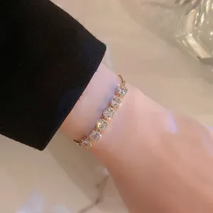 Adjustable gold plated bracelet with six sparkling square zircons on woman's wrist