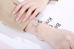 Detailed view of silver stainless steel adjustable bracelet with moon and star charms