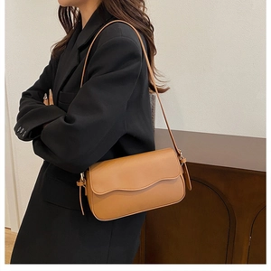 Close-up of a brown PU leather shoulder bag featuring a unique wavy flap and slim strap