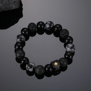 Macro shot of onyx beaded bracelet with a square gold star charm on dark reflective surface