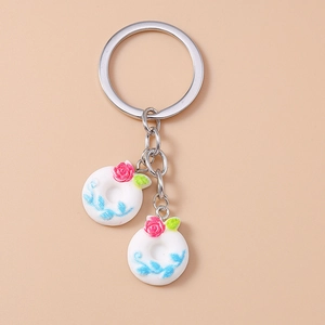 Detailed close-up of white donut keychains with pink roses and blue vine patterns