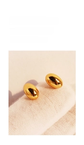 Close-up of golden bean-shaped mirror-finish stud earrings on white knit texture
