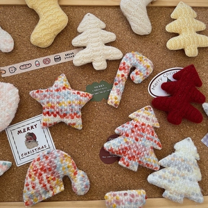 Detailed close-up of handmade knit Christmas ornaments including trees socks and stars