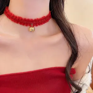 Ras du cou élégant en tricot rouge avec petit pendentif cloche dorée sur le cou