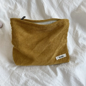 Detail of mustard yellow corduroy makeup bag with black zipper and white Sozakka label