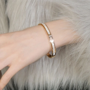 Detailed macro of gold plated steel bracelet with white shell inlay and three zircons