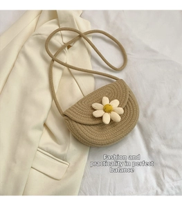 Detail of a khaki woven straw shoulder bag with a 3D white daisy flower ornament