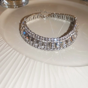 Detailed macro shot of glistening rhinestone choker on a white textured ceramic plate
