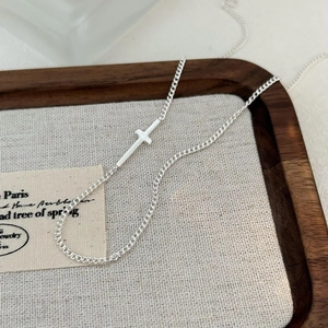Minimalist 925 sterling silver cross choker necklace displayed on a canvas frame