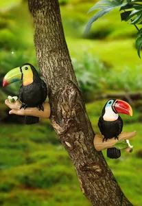 Détail d'une figurine de toucan en résine suspendue à une branche d'arbre réelle