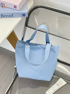 Simple light blue canvas tote bag on a chair with lifestyle props in a modern setting