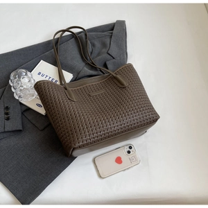 Detail of dark brown woven texture tote bag on a blazer with lifestyle accessories