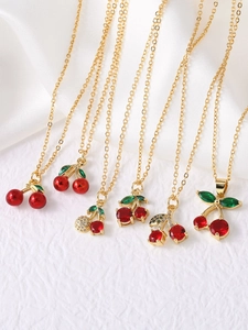 Macro shot of gold-plated cherry necklaces featuring red crystals and green leaves details