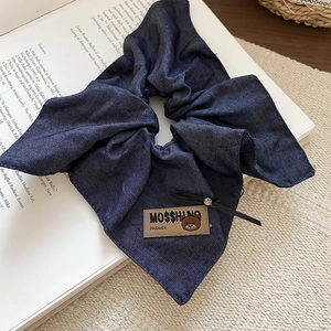 Detail of denim bow hair claw clip featuring a bear tag and sparkling rhinestone