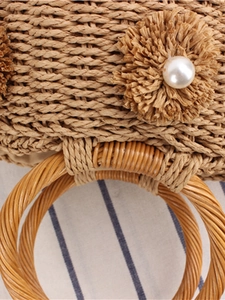 Handmade woven straw bucket bag with floral pearl detail on blue striped fabric