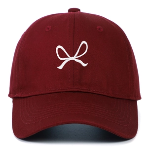 Close-up of a burgundy cotton baseball cap with white bow embroidery and curved brim