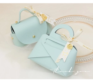 Detail of light blue leather wedding candy boxes with gold rivets and silk ribbons