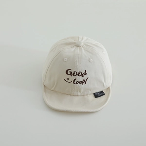 Close-up of beige cotton baby cap with Good Luck embroidery and smiley face detail