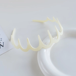 Detailed view of a cream white wavy headband with teeth on a white ceramic plate