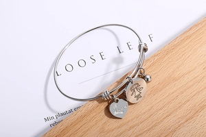 Detail of silver heart love charm and round girl pendant on expandable stainless steel bracelet