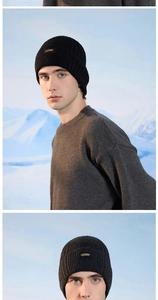 Close-up of a rib-knit beanie featuring a Studio brand tag against a snowy mountain background