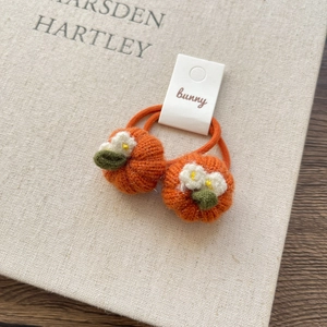 Detail of handmade crochet pumpkin hair ties with orange elastic bands and green leaf accents