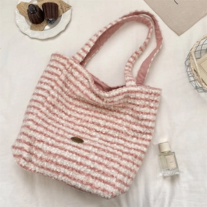 Flat lay of pink and white striped plush tote bag with gold logo on white fabric