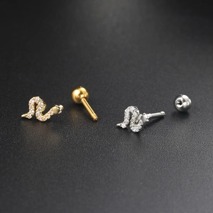 Macro shot of snake-shaped piercing studs with zircon inlay and screw ball backings