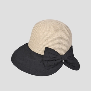 Detail of summer straw sun hat featuring a large black bow and diamond quilted texture