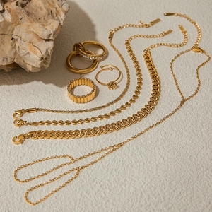 Flat lay of 18K gold titanium steel rings and necklaces with cubic zirconia and floral designs