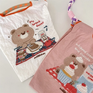 Détails des motifs d'ours brodés et des cordes tressées colorées sur sacs à cordon