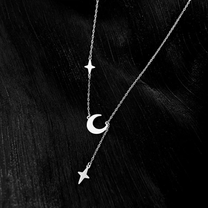 Macro view of silver titanium steel Y-necklace with crescent moon and star pendants