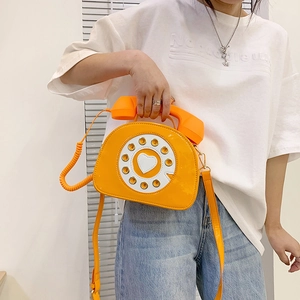 Macro shot of creative orange patent leather telephone bag with rotary dial and handle