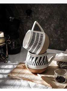 Close-up of stacked ceramic coffee mugs with hand-painted stripes and geometric patterns