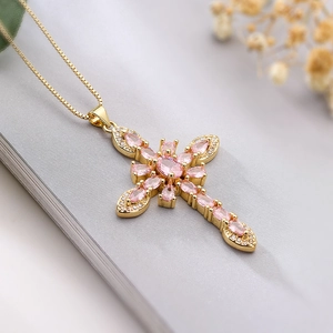 Detail of cross pendant necklace with pink marquise stones and gold plated chain