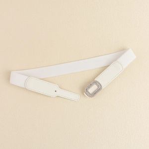 Close-up of white elastic waist belt with sparkling rhinestone buckle and faux leather finish