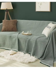 Detailed close-up of a soft green waffle weave sofa throw blanket with textured knit fabric