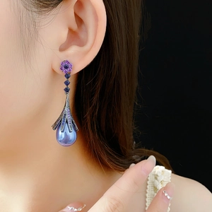 Detailed view of floral stud earring with purple pearl and blue gemstone on ear