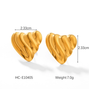 Détail macro de boucles d'oreilles cœur en or 18 carats avec texture ondulée de 2,33cm