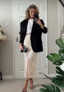 Détail de jupe en dentelle beige avec fente latérale et blazer noir chic
