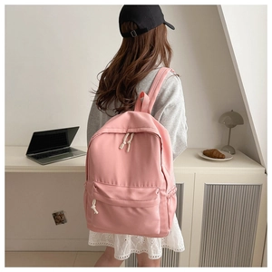 Zaino rosa minimalista in nylon da donna mostrato in un ambiente quotidiano
