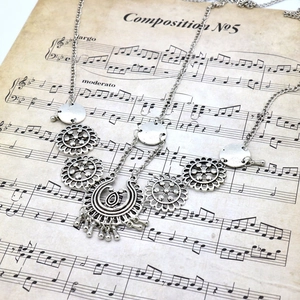 Detailed shot of bohemian silver hair chain with floral pendants on vintage music sheet