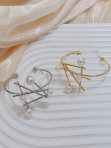 Detailed view of irregular geometric bangles with pearls in gold and silver finish